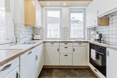 a white kitchen with white cabinets and windows at Apartments Petlin in Ortisei