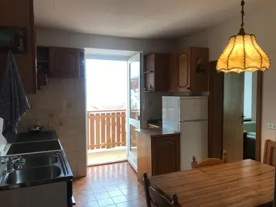 a kitchen with a wooden table and a kitchen with a refrigerator at Appartamento Pezzol in Daiano