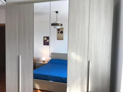 a bedroom with a blue bed and a mirror at Appartamento Pezzol in Daiano
