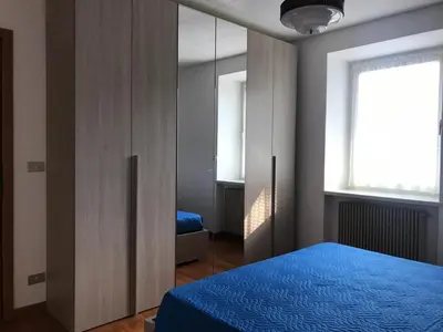a bedroom with a blue bed and a mirror at Appartamento Pezzol in Daiano
