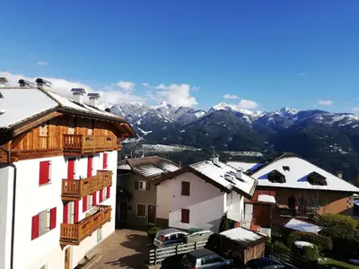 a group of buildings with snowy mountains in the background at Appartamento Pezzol in Daiano