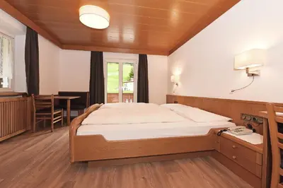 a bedroom with a large bed and a table at Hotel Garni Vanadis in Ortisei