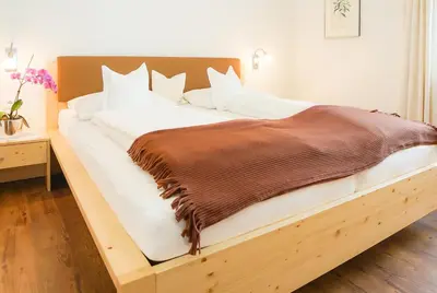 a large bed with a wooden frame in a room at Gästehaus Seitzhof in Merano