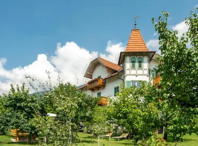 a large white house with a tower with trees at Gästehaus Seitzhof in Merano