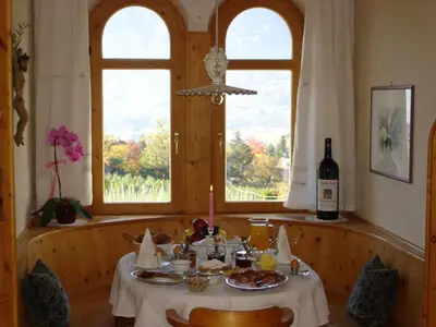 a dining table with a bottle of wine and a window at Gästehaus Seitzhof in Merano