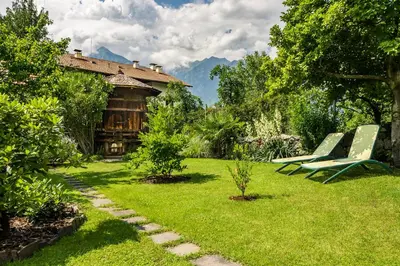a yard with two green chairs and a house at Gästehaus Seitzhof in Merano
