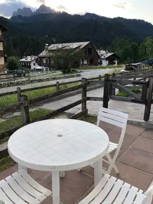 a white table and two chairs sitting next to a fence at Casa bianca in San Vito di Cadore