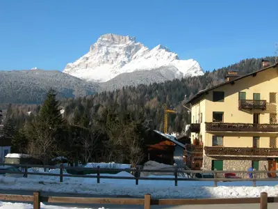 a building with a snow covered mountain in the background at Casa bianca in San Vito di Cadore