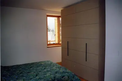 a bedroom with a bed and a dresser with a window at Casa bianca in San Vito di Cadore
