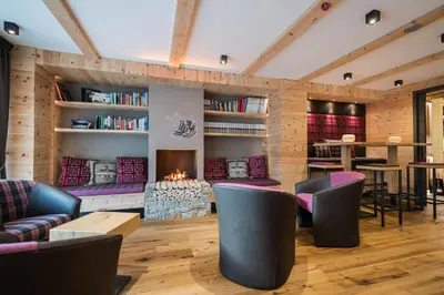 a living room with a fireplace and chairs at Hotel Ciamp in Santa Cristina in Val Gardena