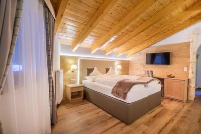 a bedroom with a bed in a room with wooden ceilings at Hotel Ciamp in Santa Cristina in Val Gardena