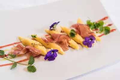 a plate of food with meat and flowers on it at Hotel Ciamp in Santa Cristina in Val Gardena