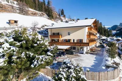 a house in the mountains with snow on the ground at Hotel Ciamp in Santa Cristina in Val Gardena