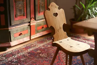 a wooden chair sitting on top of a rug at Gasthof/Albergo Dasser in San Martino in Badia