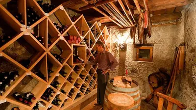a man standing in a cellar with a bunch of wine bottles at Gasthof/Albergo Dasser in San Martino in Badia