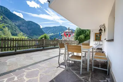a table and chairs on a balcony with a view of mountains at Panoramic Apartment 24 in Ortisei