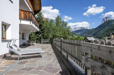 a patio with a bench and a fence and mountains at Panoramic Apartment 24 in Ortisei