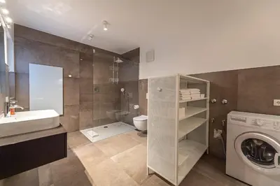 a bathroom with a sink and a washing machine at Panoramic Apartment 24 in Ortisei