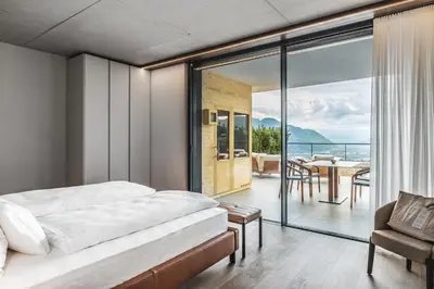 a bedroom with a bed and a balcony with a table at Arua Private Spa Villas in Merano