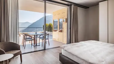 a bedroom with a bed and a balcony with a table and chairs at Arua Private Spa Villas in Merano