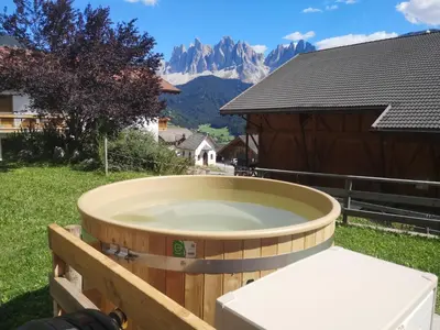 a hot tub in a yard with mountains in the background at Gruberhof Coll in Funes