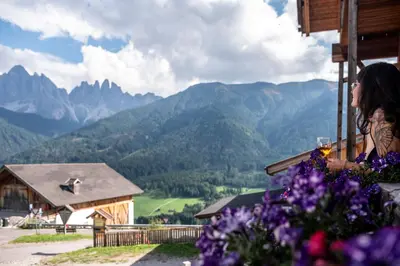 a woman standing on a balcony looking at the mountains at Gruberhof Coll in Funes