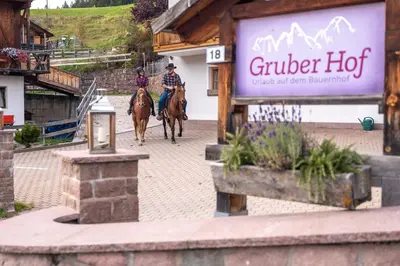 two people riding horses down a street with a sign at Gruberhof Coll in Funes