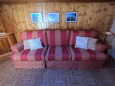 a living room with a red couch with pillows on it at ciasa de epi in Pera