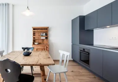a kitchen with a wooden table and white chairs at Residence Belmonte in Collalbo