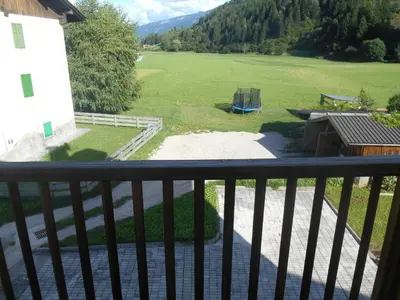 a balcony with a view of a field and a building at CASA CAMPAGNA in Cavalese