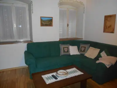 a living room with a green couch and a table at CASA CAMPAGNA in Cavalese