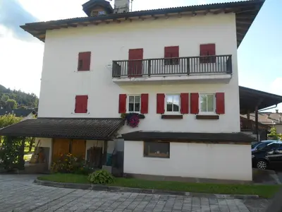 a white building with red shutters and a balcony at CASA CAMPAGNA in Cavalese