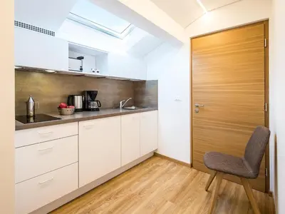 a kitchen with white cabinets and a wooden door at Apartment in Dorf Tirol near Tirol Castle in Tirolo