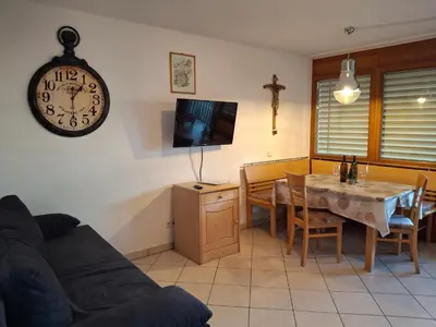 a living room with a table and a clock on the wall at Bertoldihof in Cortaccia