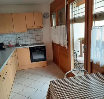 a kitchen with wooden cabinets and a table and a window at Bertoldihof in Cortaccia