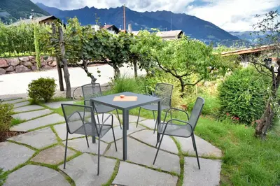 a table and chairs on a patio in a garden at Pension Georgenhof in Cermes