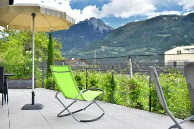a green chair sitting under an umbrella on a patio at Pension Georgenhof in Cermes