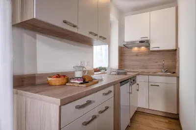 a kitchen with white cabinets and a wooden counter top at Ringlerhof in Braies
