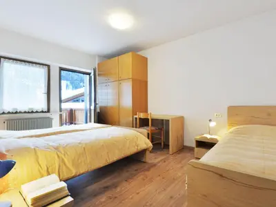 a bedroom with a large bed with a wooden headboard at Apartment Bernard-1 by Interhome in Campestrin