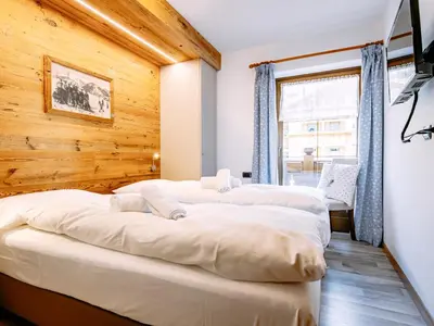 a white bedroom with a large bed and a window at Apartment Carmen-2 by Interhome in Soraga