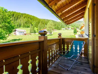 a blue rocking chair on a porch with a view at Apartment Carmen-2 by Interhome in Soraga