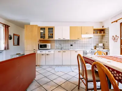 a kitchen with white cabinets and a table with chairs at Apartment Carmen-2 by Interhome in Soraga