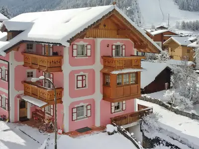 a pink house with a bench outside of it at Apartment Brunel-1 by Interhome in Pozza di Fassa