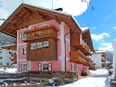 a pink building with wooden balconies on it at Apartment Brunel-1 by Interhome in Pozza di Fassa