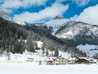 a house in the snow with mountains in the background at Apartment Ardoney-1 by Interhome in Campitello