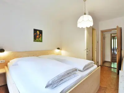 a bedroom with a large white bed with a pendant light at Apartment Puntea by Interhome in Ortisei
