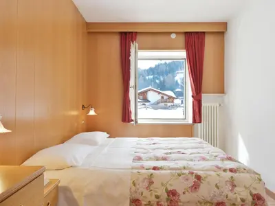 a bedroom with a large bed and a window at Apartment Cincelli - Latemar by Interhome in Pozza di Fassa