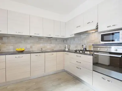 a kitchen with white cabinets and stainless steel appliances at Apartment Bernard-2 by Interhome in Campestrin
