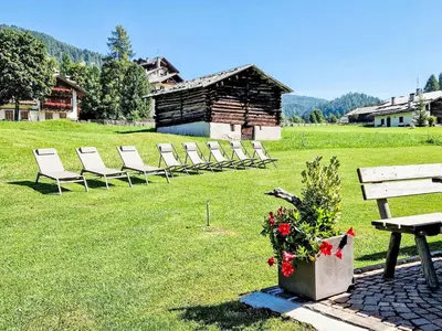 a row of chairs sitting in a field with a bench at Apartment Chalet Baita Tabià Dolomites by Interhome in Bellamonte