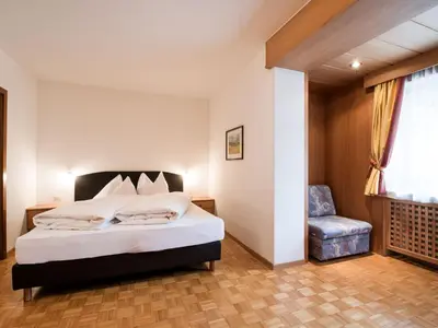 a bedroom with a bed and a chair and a window at Apartment Ornella-4 by Interhome in Ortisei